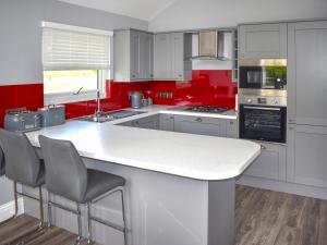 a kitchen with red walls and a white counter top at Oak Park One - Uk50062 in Tiverton