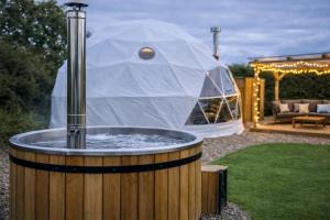 a hot tub with a tent in a yard at Grass Roots Retreat in Llanstadwell