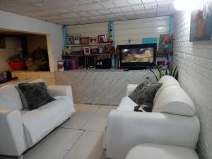 a living room with two white couches and a tv at Recanto Aconchego in Torres