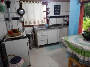 a kitchen with white cabinets and a sink and a table at Recanto Aconchego in Torres