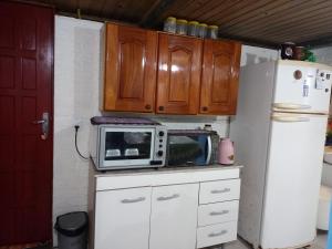 a kitchen with a microwave and a refrigerator at Recanto Aconchego in Torres +6 photos