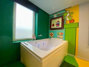 a childs bathroom with a tub in a green room at Retro Gaming Mood - Arcade Games - Jacuzzi - Sauna - Switch 2 in Courcelles