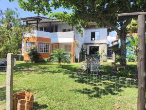 a house with a fence in front of it at Treehouse albatroz hospedaria in Imbituba