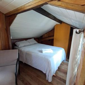 a bedroom with a white bed in a attic at Treehouse albatroz hospedaria in Imbituba