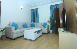 a living room with a white couch and blue pillows at New apartment in Hattigauda in Khadkagaon