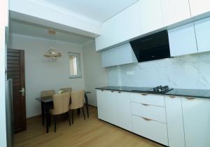 a kitchen with white cabinets and a table with chairs at New apartment in Hattigauda in Khadkagaon