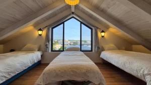 two beds in a room with a large window at קיבוץ שדה נחום Green House in Sede Naẖum