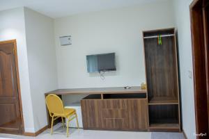 ein Zimmer mit einem Schreibtisch mit Fernseher und einem gelben Stuhl in der Unterkunft Rainforest Hotel in Odumasi