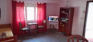 a living room with red curtains and a table and a tv at Casa 7 personas in Villa Gesell