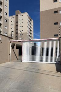 a white fence in front of some tall buildings at Apartamento Loretto in Espirito Santo Do Pinhal