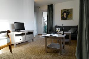 a living room with a tv and a table with a wine glass at Das Weinberghaus in Fellbach