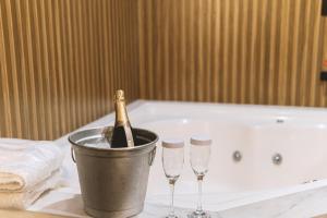 a bottle of champagne in a bucket next to three wine glasses at Paris Motel in Matão