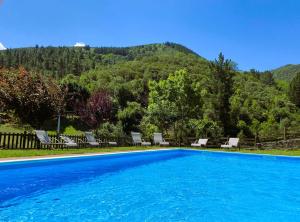 a swimming pool with chairs and a mountain in the background at Hotel Finca Malvasia - Adults only in Cabezón de Liébana
