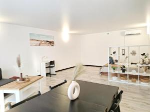 a living room with a table and a bedroom at Kopų tako apartamentai in Melnragė
