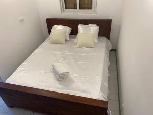 a large bed with white sheets and pillows at Bungalow cerise in Morne-à-lʼEau