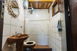 a bathroom with a sink and a toilet and a mirror at Green House Chalé, hostel e pousada in Saquarema +62 photos