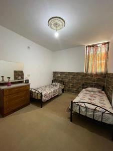 a bedroom with two twin beds and a dresser at Jerash Skyline in Jerash