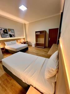a room with two beds in a hotel room at Gran Vale Hotel in Guanhães