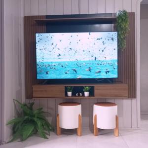 a television screen with two stools in a room at Casa de verão vó judite -praia Sulmar- 4 quartos in Balneário Gaivotas