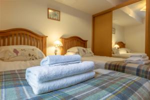 a hotel room with two beds with towels on top at Torr Apartment Raven in Fort Augustus