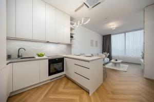 a kitchen with white cabinets and a wooden floor at Apollo One, 1BR Signature Residence in Nivy