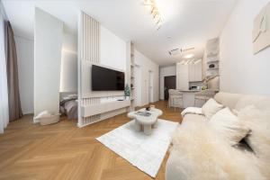 a white living room with a couch and a tv at Apollo One, 1BR Signature Residence in Nivy