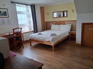 a bedroom with a bed and a desk and a window at The Albert Hotel in Gloucester