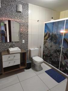 a bathroom with a toilet and a sink and a mirror at Casa Bilbao in Maricá