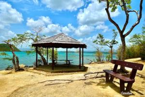 a bench sitting on a beach with a gazebo at L'Aparté des hibiscus in Les Trois-Îlets