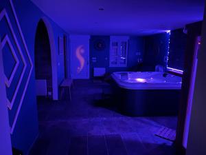 a dark room with a tub in a purple room at Evad&vous in Recquignies