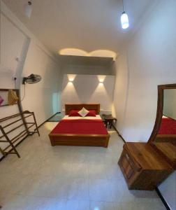 a bedroom with a red bed and a mirror at Kanchi's please in Udawalawe