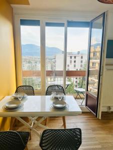 a dining room with a table and chairs and a balcony at Appartement Bellevue - T2 vue montagne - calme - parking gratuit - 4 personnes in Meylan