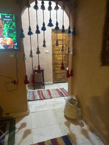 a living room with a tv and a wall with beads at Bandres farm in Siwa