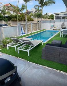 a backyard with a swimming pool with lounge chairs and a table at Apartment with private pool in Ashkelon