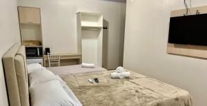 a room with two beds and a flat screen tv at Pousada Cores De Outono in Canela