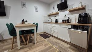 a kitchen with white cabinets and a table with chairs at Hortensjowe Zacisze in Wolibórz