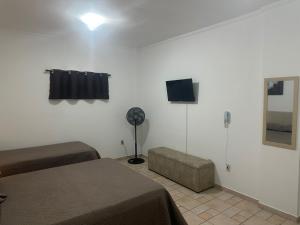 a room with two beds and a fan and a television at Kitnet no interior de São Paulo 22 in Serra Negra