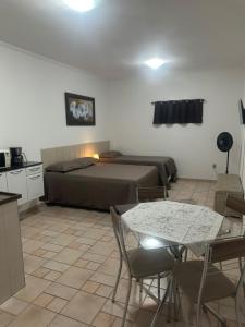 a bedroom with a bed and a table and chairs at Kitnet no interior de São Paulo 22 in Serra Negra