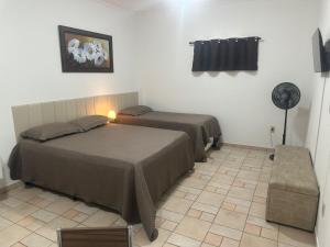 a bedroom with two beds and a fan at Kitnet no interior de São Paulo 22 in Serra Negra