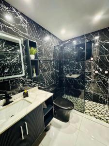 a black bathroom with a toilet and a sink at Brand New Luxe Apartment 1 in Carolina