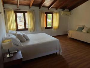 a bedroom with a large white bed and two windows at Costanera 61, frente a la laguna in Chascomús