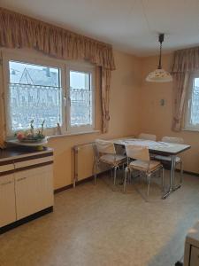 a kitchen with a table and chairs and windows at Lottes FeWo in Hasselroth