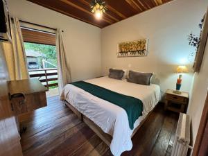 a bedroom with a bed and a window at Roame Hosting Boutique in Campos do Jordão
