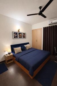 a bedroom with a blue bed with a ceiling fan at Warm Embrace in Noida +5 photos