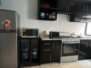 a kitchen with a stove and a microwave and a refrigerator at Cuarto a 4min del aeropuerto in Guadalajara