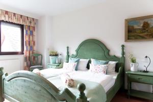 a bedroom with a green bed with pillows at Landhotel Marienthaler Hof in Marienthal
