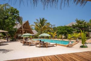 a pool at a resort with people sitting on chairs and umbrellas at Hostel 197 in Nungwi
