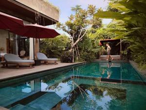 a woman is standing next to a swimming pool at Pigstone Design Studios Beachfront in Tanah Lot