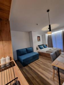 a bedroom with a bed and a blue couch at SKYLINE apartments Kopaonik in Kopaonik