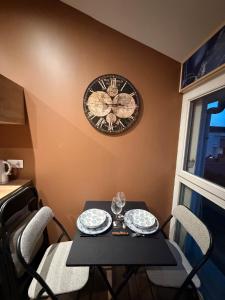 a table with chairs and a clock on the wall at Le Saphir avec Parking gratuit in Montigny-le-Bretonneux